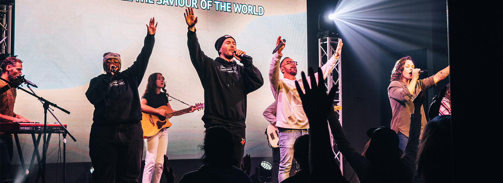 Singers on a stage with their hands in the air