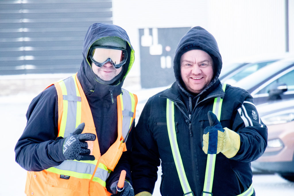 Two men outside, dressed to help direct parking