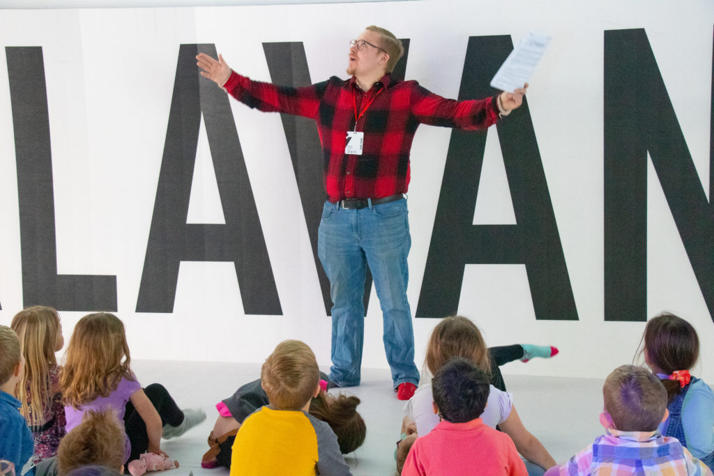 Man teaching children who are sitting on the floor